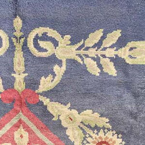 Textured blue rug featuring ornate floral scrollwork in beige, pale green, and salmon pink.