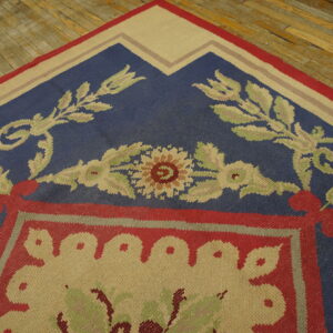 Floral-patterned flatweave rug in blue, red, and tan on rustic hardwood planks.