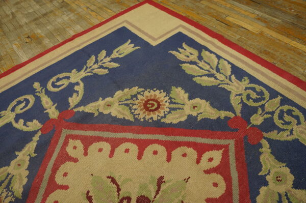 Floral-patterned flatweave rug in blue, red, and tan on rustic hardwood planks.
