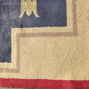 High pile rug corner featuring borders in red, light beige, and taupe surrounding a navy blue field.