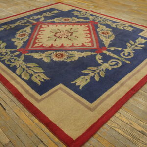 Blue and beige area rug with a detailed red and green floral pattern rests on rustic wood flooring.
