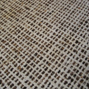 Low-pile textured rug in white and brown woven in a dense, diagonal grid over wood flooring.