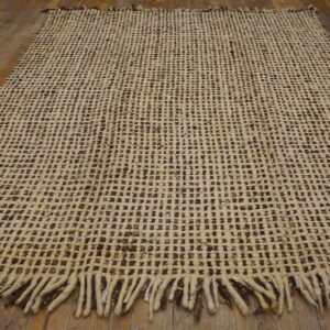Loosely woven cream and dark brown square-patterned rug with heavy fringe on wood floors.