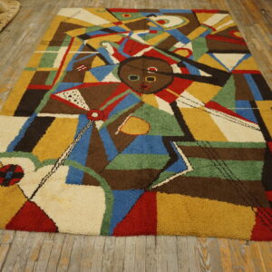 Colorful shaggy rug with an abstract face design and geometric shapes on distressed wood flooring.