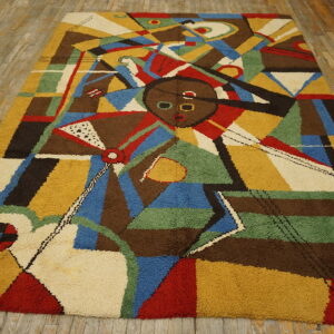 High-pile rug with abstract geometric patterns in mustard, red, blue, and brown on distressed wood flooring.