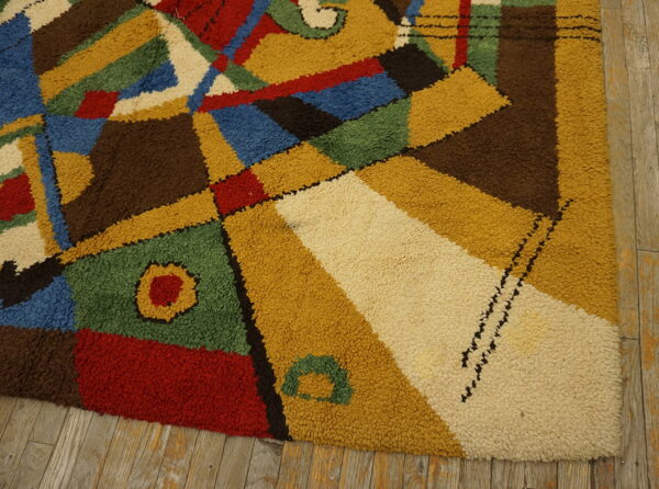 High-pile rug with geometric shapes in primary colors and brown rests on weathered wood planks.