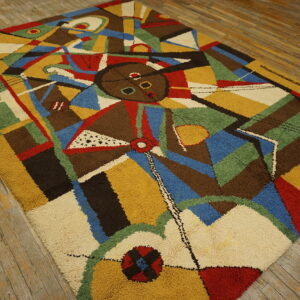 High pile rug featuring a multi-color abstract cubist design laid on distressed wooden floorboards.