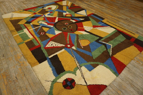 High pile rug featuring a multi-color abstract cubist design laid on distressed wooden floorboards.
