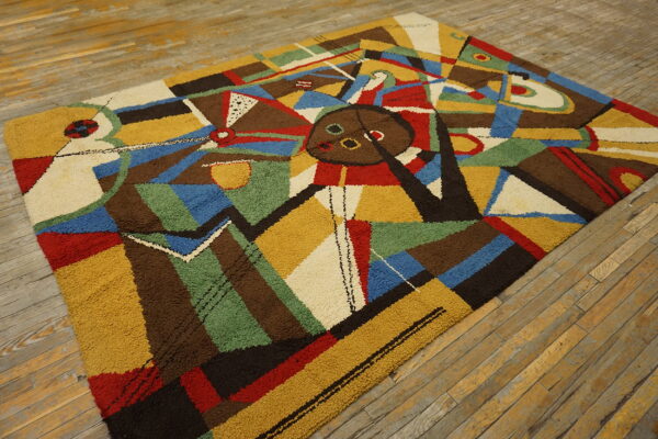Textured rug with a colorful abstract geometric design in primary colors and earth tones on wood planks.