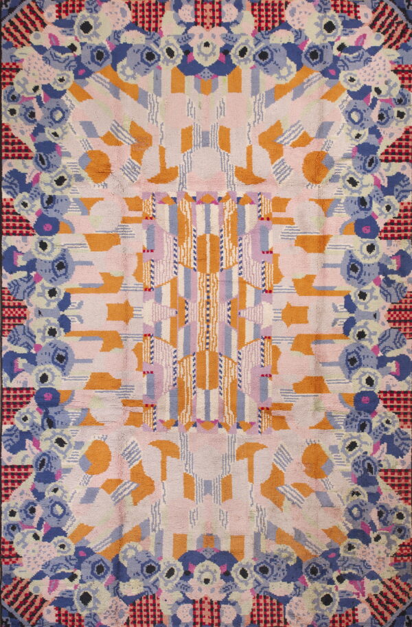 Textured rug displaying a complex symmetrical pattern of orange, pink, blue, lavender, and checkered motifs.