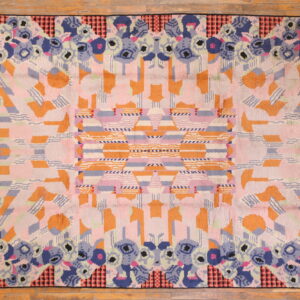 Abstract high-pile rug featuring a border of blue florals and a pink and orange geometric center on wood flooring.