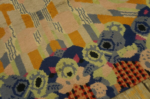 Textured multicolor abstract rug featuring blocks, zigzag lines, and stylized floral motifs on wood flooring.