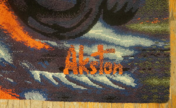 Textured rug detail with orange letters reading "aksion" surrounded by blue, black, and green loops.