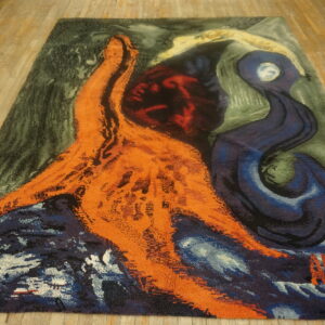 Shaggy abstract rug with bright orange and navy shapes contrasting a dark green background on wood planks.