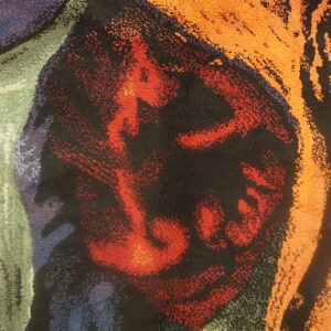 Plush, abstract rug detail features bold shapes in orange, black, red, purple, and green colors.