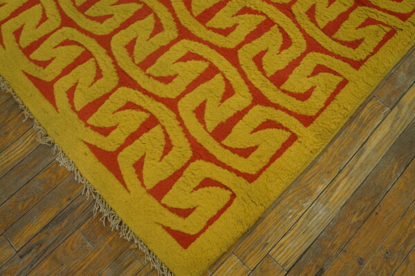 A high-pile rug with a bold yellow and orange geometric pattern sits on rustic wood floors.