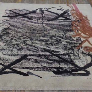 Abstract area rug in cream with sprawling black and terracotta strokes on weathered wood planks.