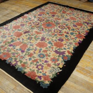 Medium-pile rug featuring multi-colored flowers on cream, framed by a thick black border, placed on plank flooring.
