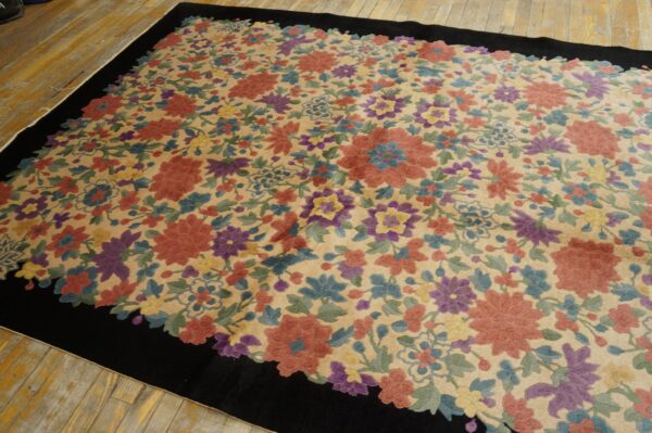 Beige rug featuring vibrant red, purple, and blue floral motifs, framed by a thick black border on wood flooring.