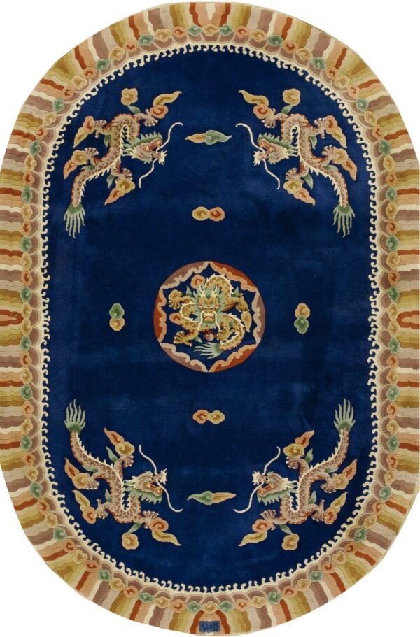 Deep blue oval rug with an ornate dragon motif surrounded by a striped border in earth tones.