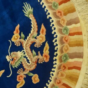 Plush blue rug displaying a detailed dragon motif and a scalloped, multi-toned border on wood floor.