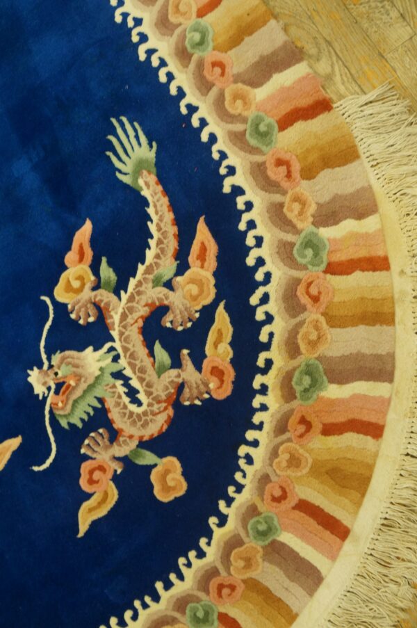 Plush blue rug displaying a detailed dragon motif and a scalloped, multi-toned border on wood floor.