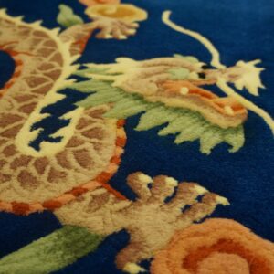 Deep blue rug with a carved dragon pattern in beige, brown, orange, and green colors.