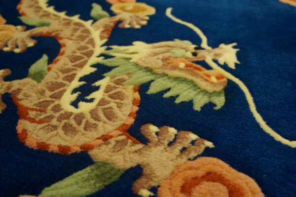 Deep blue rug with a carved dragon pattern in beige, brown, orange, and green colors.