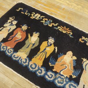 Long black runner rug featuring colorful robed figures and blue cloud motifs on wood flooring.
