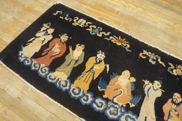 Long black runner rug featuring colorful robed figures and blue cloud motifs on wood flooring.