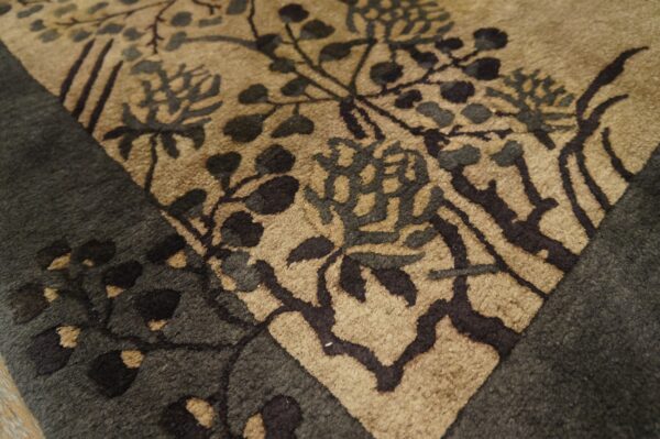 Close-up view of a high-pile rug with a dark gray border and a tan floral field.