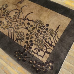 A brown and tan floral rug with a dark border lies on distressed light wood flooring.