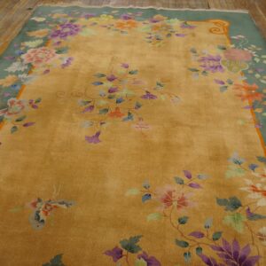 Golden yellow rug with a sage green border and multicolor florals, placed on distressed wood floors.