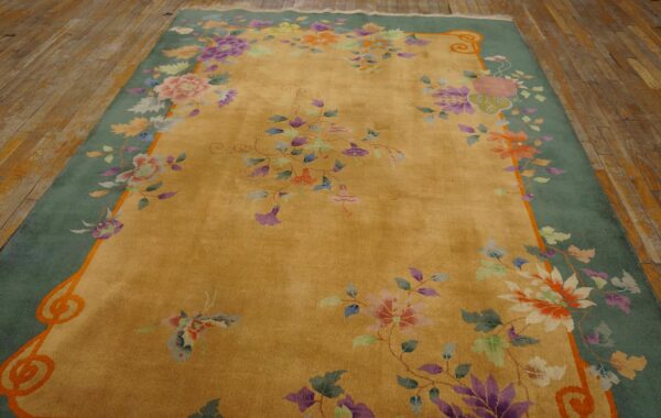 Golden yellow rug with a sage green border and multicolor florals, placed on distressed wood floors.