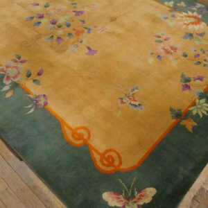 A golden rug featuring a wide teal border and colorful floral and butterfly motifs rests on a wood floor.