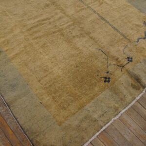 A textured mustard-yellow rug with a faded teal border displays sparse dark motifs on wood flooring.