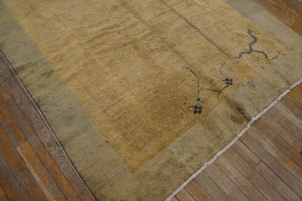 A textured mustard-yellow rug with a faded teal border displays sparse dark motifs on wood flooring.