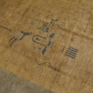 Gold and dark gray low-pile rug featuring stylized abstract and floral motifs on wood flooring.