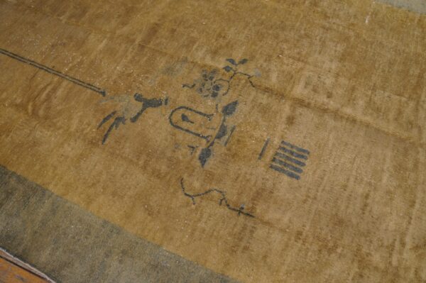 Gold and dark gray low-pile rug featuring stylized abstract and floral motifs on wood flooring.