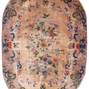 Tan oval rug featuring a dense multicolored floral bouquet and a wide mauve border with blue accents.