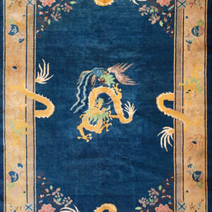Deep blue rug with an ornate golden dragon pattern and light tan border containing floral and vase motifs.