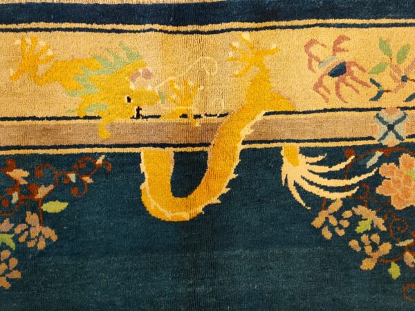 Teal and tan rug detail showing a bright yellow dragon motif, floral accents, and a shaggy medium pile.