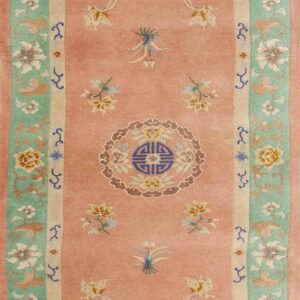 Muted pink runner rug with diverse floral designs, butterflies, and a prominent mint green border.