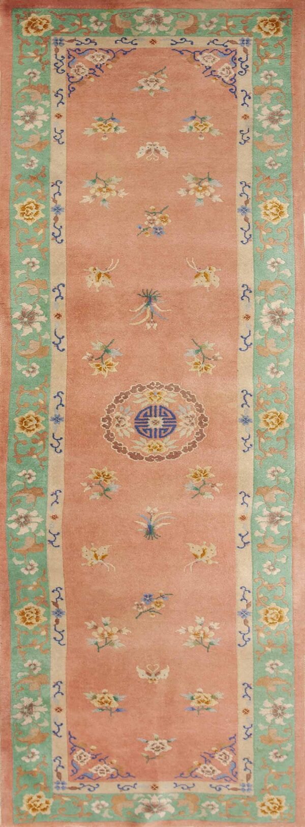 Muted pink runner rug with diverse floral designs, butterflies, and a prominent mint green border.