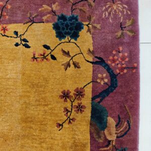 Gold and plum rug border with teal, pink, and tan flowering branch motifs on white tile.