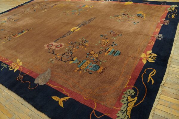 Shimmering tan rug with colorful floral and vase motifs, featuring wide navy and red borders on wood planks.