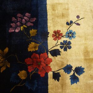 Multicolored floral design spans a vertical navy and gold background, visible next to wood flooring.
