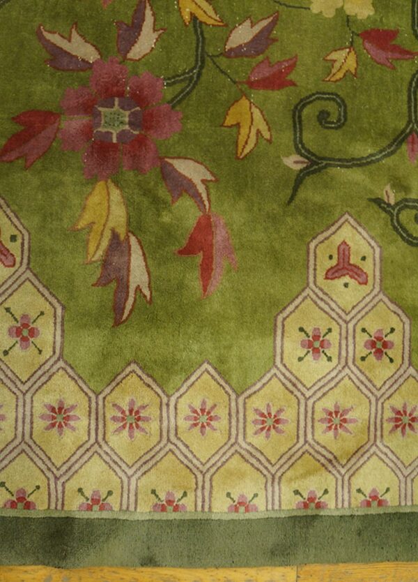 Plush olive green rug with red floral vines and a complex geometric border of interlocking yellow hexagons.