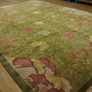 Shaggy green rug with scrolling pink and yellow floral patterns resting on light wood flooring.