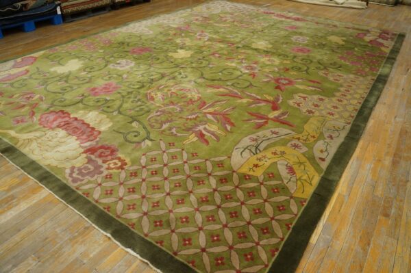 Plush olive green rug with intricate pink, red, and cream floral designs covers a light wood floor.